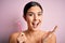 Young beautiful girl using shaver for depilation standing over isolated pink background very happy and excited, winner expression