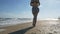 A young beautiful girl walks along the shore and enjoys the wind while walking along the beach by the bay