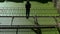 Young beautiful girl walks on thin ruined rusty metal bridge over green water.