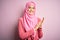Young beautiful girl wearing muslim hijab standing over isolated pink background clapping and applauding happy and joyful, smiling