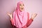 Young beautiful girl wearing muslim hijab standing over isolated pink background crazy and mad shouting and yelling with