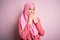 Young beautiful girl wearing muslim hijab standing over isolated pink background laughing and embarrassed giggle covering mouth