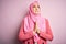 Young beautiful girl wearing muslim hijab standing over  pink background begging and praying with hands together with hope