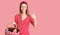 Young beautiful girl wearing picnic basket smiling happy and positive, thumb up doing excellent and approval sign