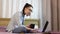 A young beautiful girl working from her laptop while drinking coffee from a black cup.