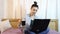 A young beautiful girl working from her laptop while drinking coffee from a black cup.