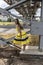 Young beautiful girl in yellow smart dress on a background of metal structures in the industrial zone, heating