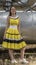 Young beautiful girl in yellow smart dress on a background of metal structures in the industrial zone, heating