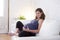 Young beautiful happy 8 or 9 months pregnant woman at home living room couch holding big belly