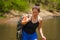 Young beautiful and happy Asian Chinese woman carrying backpack trekking on mountains crossing river enjoying holiday nature and