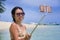 Young beautiful and happy Asian Chinese woman having fun on sea water taking selfie picture with mobile phone camera on paradise b