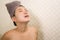 Young beautiful and happy Asian Chinese woman with head wrapped in towel smiling fresh and cheerful after taking shower enjoying