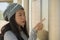 Young beautiful and happy Asian Chinese woman waiting the train on station platform bench checking travel and itinerary schedule