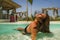 Young beautiful and happy Asian Indonesian woman in bikini swimming in tropical island pool resort enjoying luxury and exotic