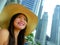 Young beautiful and happy Asian Korean tourist woman in Summer hat luxury at hotel infinity pool enjoying city buildings view chee