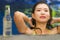 Young beautiful and happy Asian Korean woman in bikini enjoying vacation at swimming pool relaxed and cheerful bathing at villa or