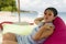 Young beautiful and happy Asian Korean woman in chic Summer dress and hipster sunglasses posing relaxed at tropical beach relaxed