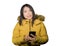 Young beautiful and happy Asian Korean woman in warm yellow feather jacket with fur hood using mobile phone smiling with sweet
