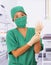 Young beautiful and happy Asian medicine doctor or chief hospital nurse in green scrubs and surgey hat and mask putting  latex