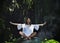 Young beautiful and happy Asian practicing yoga outdoors at amazing peaceful and fresh tropical background sitting in rock doing r