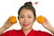 Young beautiful and happy Asian woman in traditional Chinese New Year red dress holding orange fruit as symbol of prosperity