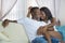 Young beautiful happy black afro American couple in love relaxed at modern home living room cuddling sweet on sofa couch smiling