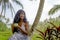 Young beautiful and happy black afro American tourist woman drinking coffee or tea visiting jungle plantation in Thailand or Vietn