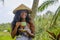 Young beautiful and happy black afro American tourist woman drinking coffee or tea visiting jungle plantation in Thailand or Vietn