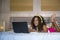 Young beautiful happy black Afro American woman at home bedroom lying cheerful on bed listening to internet music with headphones