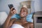 Young beautiful and happy black afro american woman lying at home couch relaxed smiling cheerful using internet social media app o