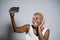 Young beautiful and happy black afro American woman smiling excited taking selfie picture portrait with mobile phone or recording