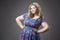 Young beautiful happy blonde plus size model in dres, xxl woman portrait on gray studio background