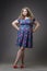 Young beautiful happy blonde plus size model in dress and shoes, xxl woman on gray studio background