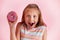Young beautiful happy and excited blond girl 8 or 9 years old holding donut on her hand looking spastic and cheerful in sugar addi