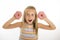 Young beautiful happy and excited blond girl 8 or 9 years old holding two donuts playing cheerful in sugar calories and unhealthy