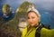 Young beautiful and happy hiker woman with backpack hiking on sea mountain cliff taking selfie portrait with mobile phone enjoying