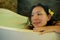 Young beautiful and happy relaxed Asian Korean woman enjoying indulging milk bath in bathtub at luxury Spa smiling delighted