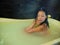 Young beautiful and happy relaxed Asian Korean woman enjoying indulging milk bath in bathtub at luxury Spa smiling delighted