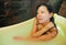 Young beautiful and happy relaxed Asian Korean woman enjoying indulging milk bath in bathtube at luxury Spa smiling delighted