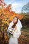 Young beautiful happy slim smiling bride on autumn forest background