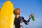 Young beautiful and happy surfer girl holding yellow surf board smiling cheerful drinking beer bottle enjoying summer holiday