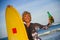 Young beautiful and happy surfer woman holding yellow surf board smiling cheerful drinking beer bottle enjoying summer holida