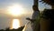 Young beautiful happy woman wears bathrobe drinks coffee in the morninig during amazing sunrise stands on the terrace of