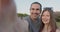 A young beautiful heterosexual couple with braces takes a selfie in the park.