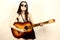 Young beautiful hippie playing guitar on light background