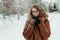 Young beautiful hipster woman in knitted scarf standing in the park and smiling. Winter fashion