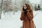 Young beautiful hipster woman in knitted scarf standing in the park and smiling. Winter fashion