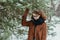 Young beautiful hipster woman in knitted scarf standing in the park and smiling. Winter fashion