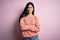 Young beautiful hispanic fashion woman wearing animal print sweater over pink background skeptic and nervous, disapproving