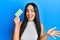 Young beautiful hispanic girl holding birth control pills celebrating achievement with happy smile and winner expression with